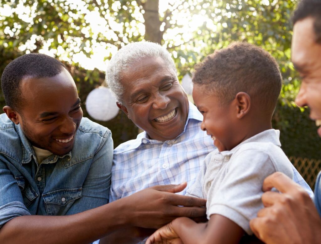 grandfather, sons and grandson talking in a garden