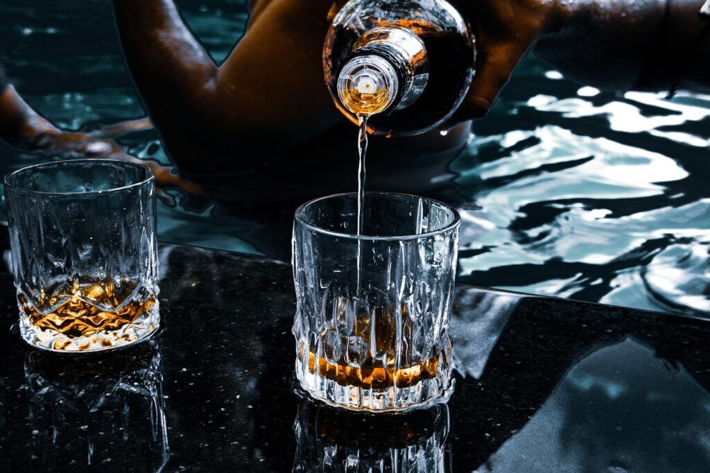 A person pouring a drink on a glass