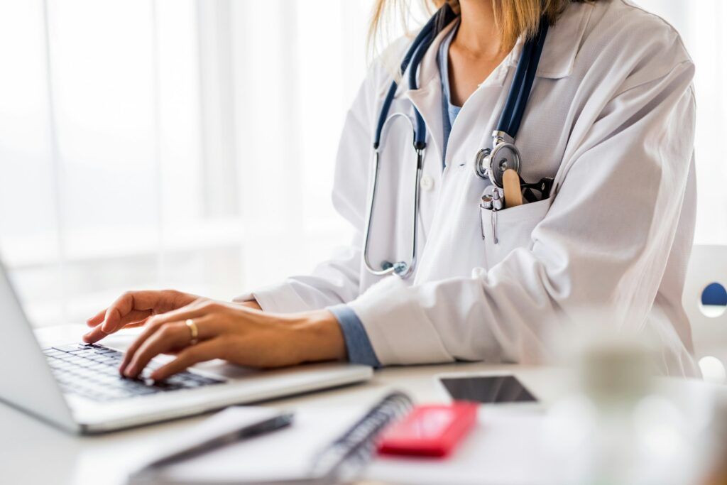 A person wearing a white robe typing on a laptop