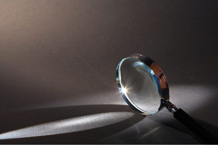 magnifying glass standing on dark surface with beam of light