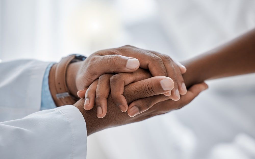 A doctor and patient holding hands