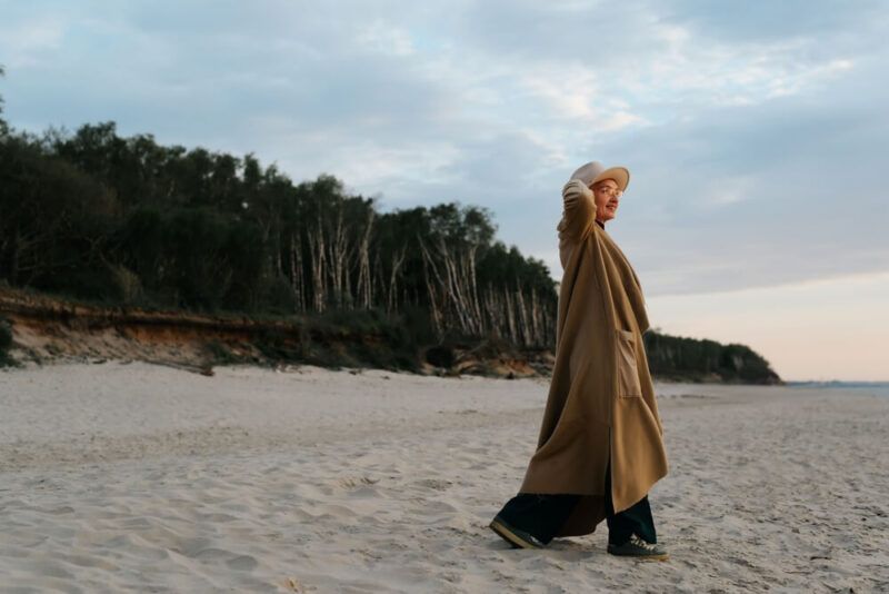 Happy senior stylish woman walking on beach in evening