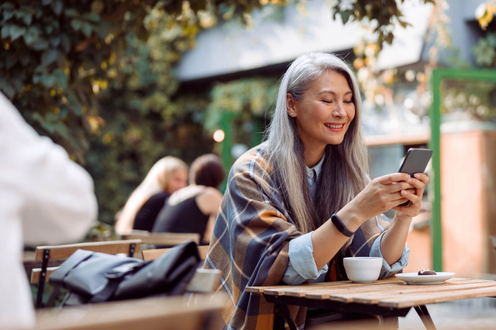 Happy mature Asian woman surfs internet on mobile phone