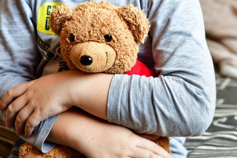 Boy in pijamas huggig a teddy bear toy