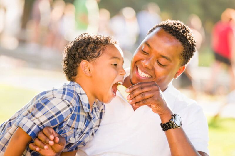 African American Father and Mixed Race Son Eating an Apple