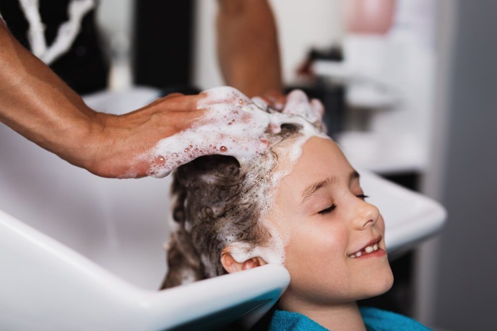 Hairdresser washing hair of cute girl in hair salon