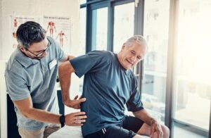 Chiropractor And Elderly Man With Back Pain