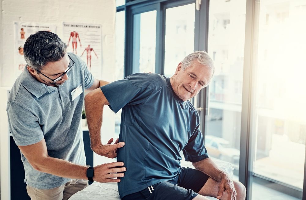 Chiropractor And Elderly Man With Back Pain