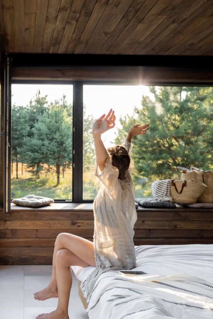 Woman wakes up in a country house or hotel with panoramic windows