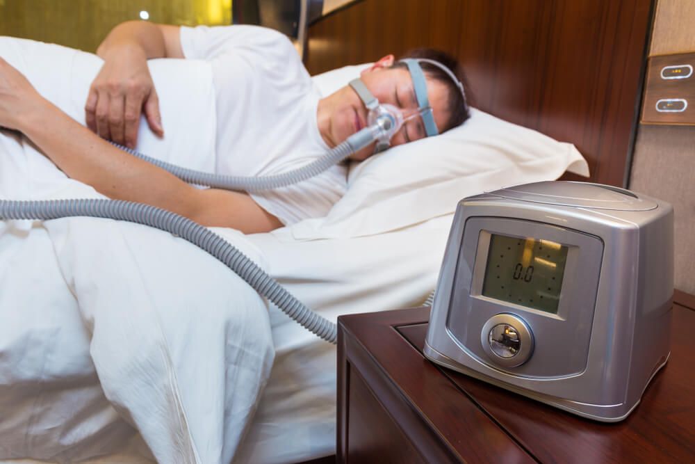 CPAP machine sitting on the bedside table next to the bed