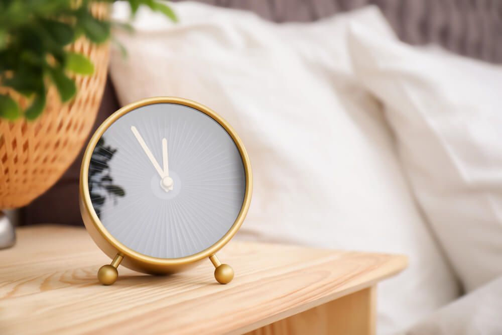 Analog alarm clock on table in bedroom