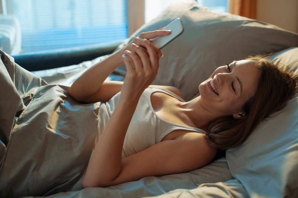Young woman using a smart phone in the bed